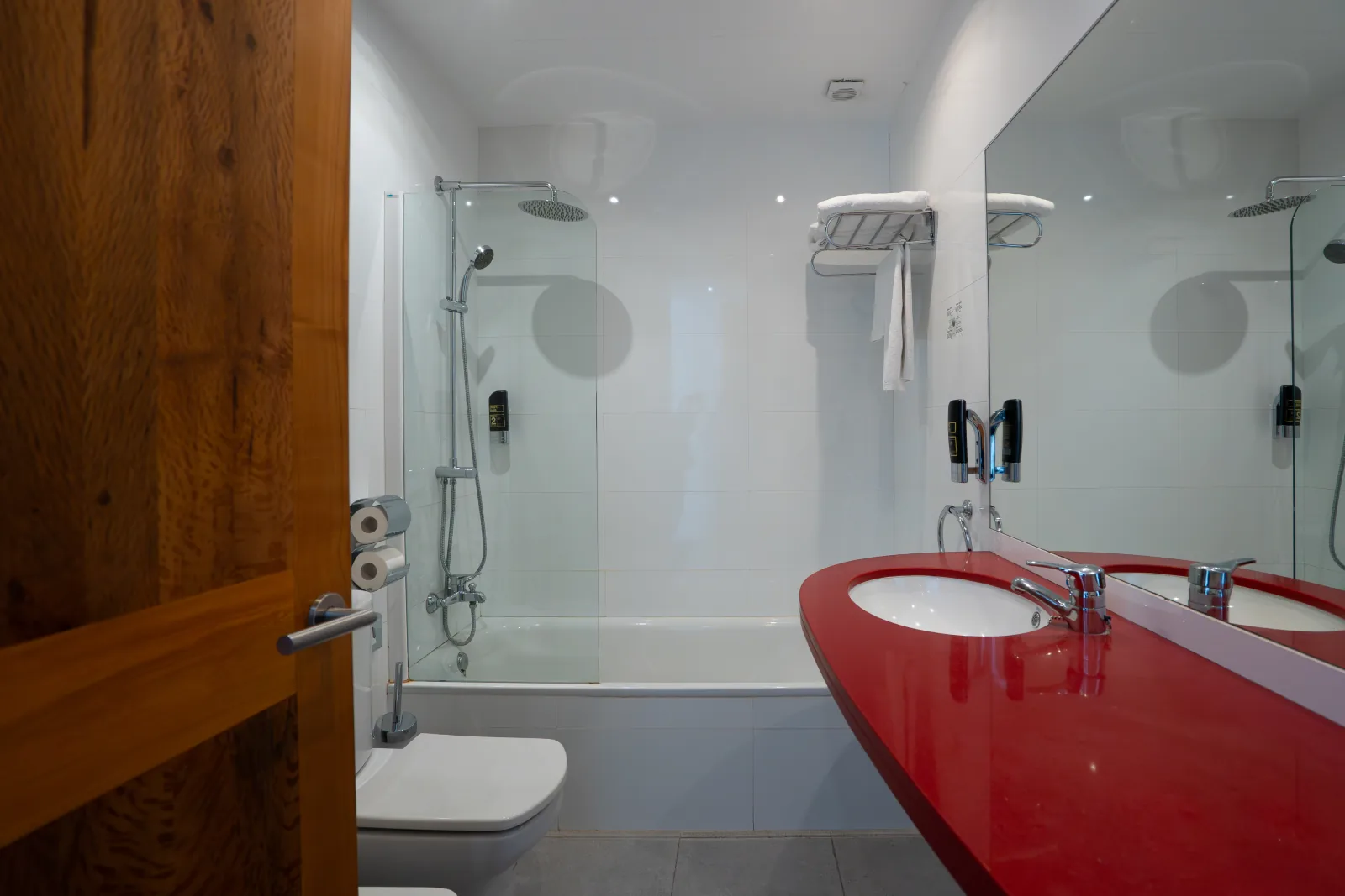 Lavabo en rojo y ducha con mampara de cristal en baño de L'Hostal Pollença