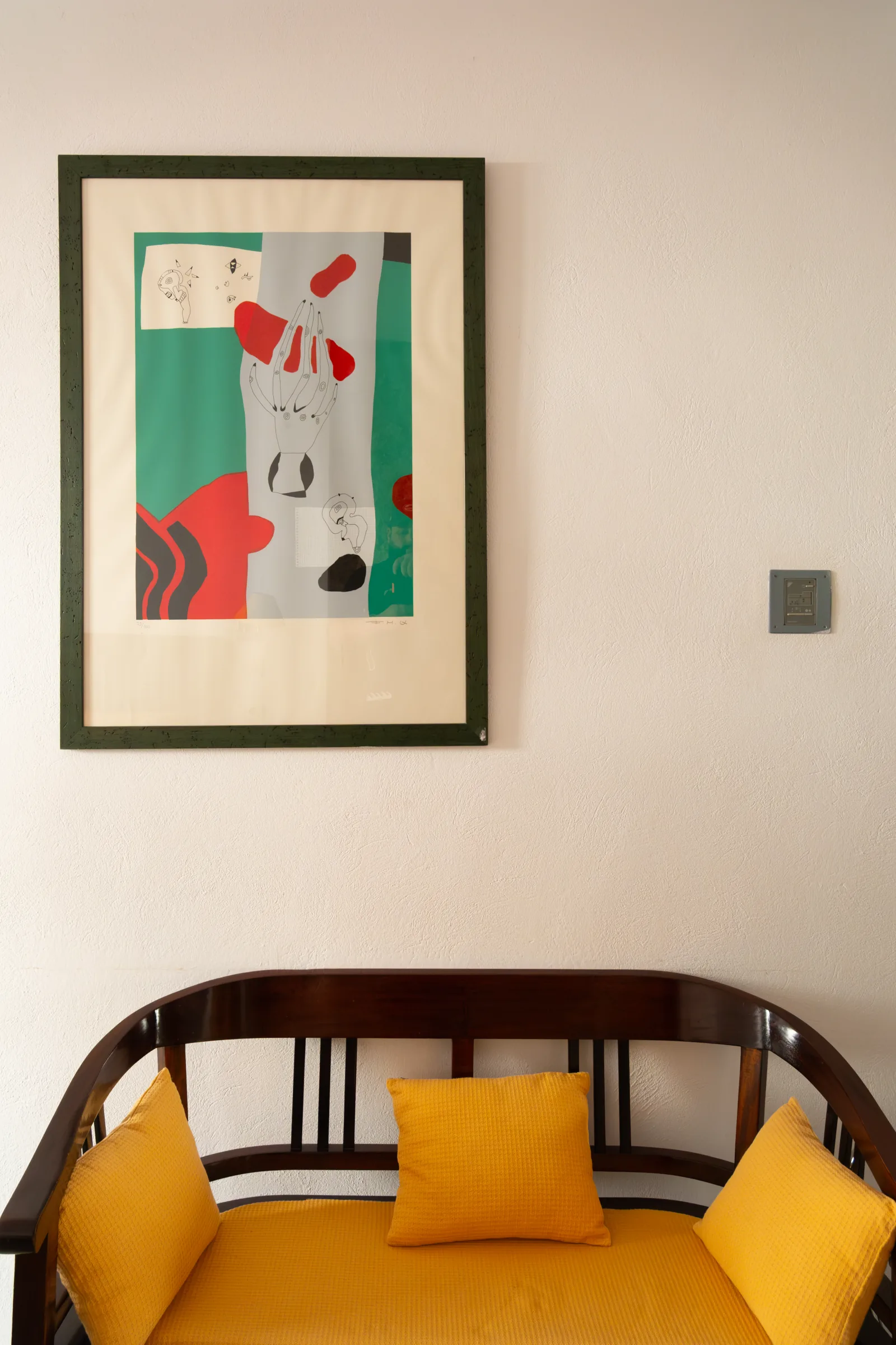 Cuadro original de Aina Cifre con motivo de mano sobre banco amarillo, arte en L'Hostal Pollença